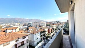 Un quartier résidentiel caractérisé par des toits recouverts de tuiles en terre cuite, un mélange d’architecture moderne et traditionnelle, et une vue dégagée sur les montagnes lointaines.