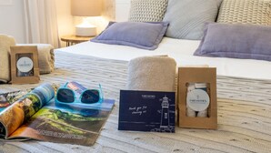 Une chambre d’hôtel bien rangée, avec un lit, des oreillers, une lampe et un magazine.