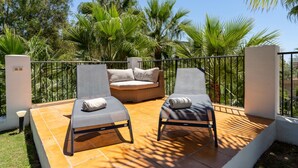 Un balcon avec deux fauteuils de relaxation, un petit canapé et un mur blanc.