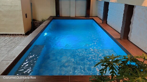 A rectangular swimming pool with clear blue water, surrounded by tiled flooring and walls.