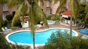 Una piscina circondata da palme e un edificio con tetto rosso.