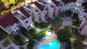 Un edificio residenziale a più piani con un cortile centrale che include una piscina circondata da sedie a sdraio.