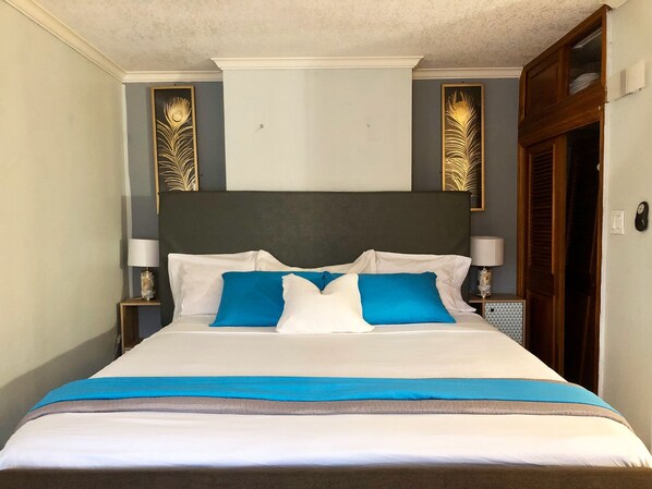 A neatly made bed with white and blue bedding, two nightstands with lamps, and decorative wall panels.