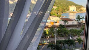 A view through a window with a view of a coastal area, including buildings and palm trees. - Beachside Tropics - King Bed (Ocho Rios)