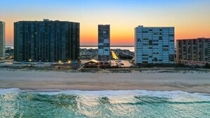Un paysage urbain côtier avec de hauts immeubles, une plage et un coucher de soleil.