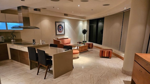 Eine moderne Küche mit einer zentralen Kochinsel, dunklen Stühlen und einer Couch.