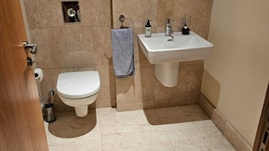 Ein Badezimmer mit Toilette, Waschbecken und Duschbereich.