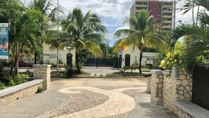 A paved entrance with a stone pathway leading to a gated area, surrounded by palm trees and a building with a sign reading "Hernandez's Point". - Beachfront Escape (Ocho Rios)