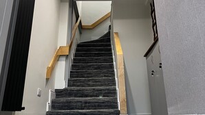 A modern staircase with a geometric patterned floor, a wooden handrail, and a ceiling with recessed lighting. - 53 Luxury Rooms  (Maynooth)