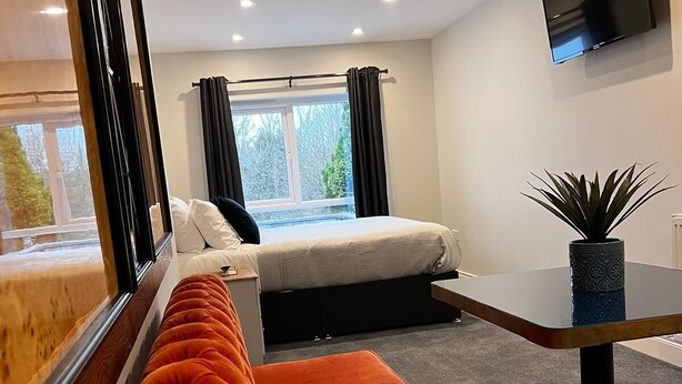 A modern room with a bed, a sofa, a small table, and a TV. - 53 Luxury Rooms  (Maynooth)