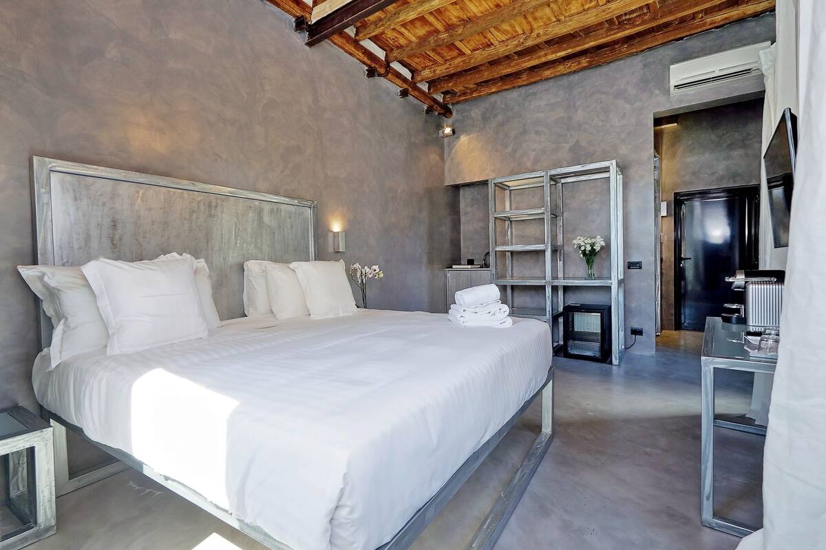 A modern bedroom with a large bed, built-in shelves, and a minimalist design.
