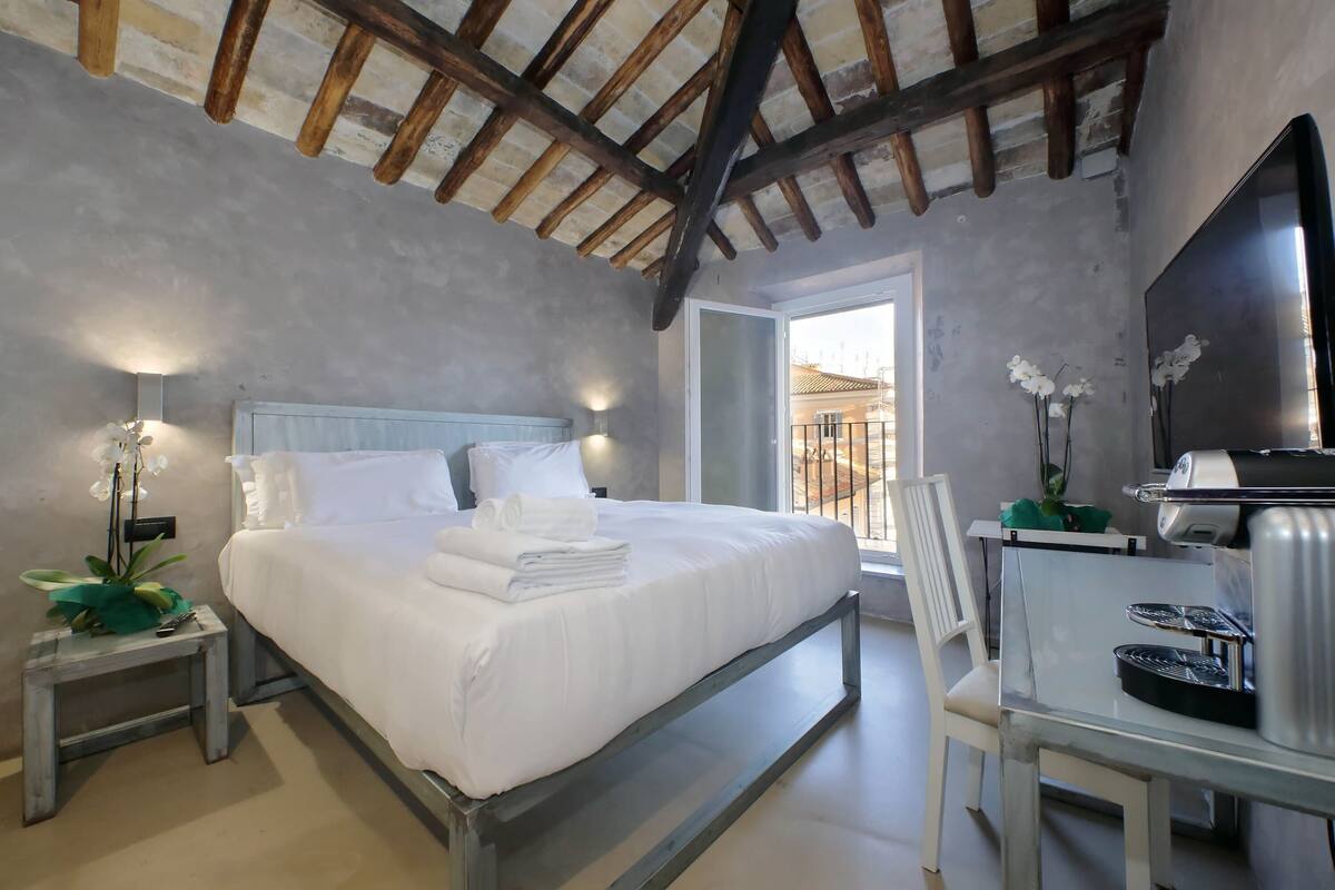 A bedroom with a bed, bedside table, and a desk with a chair.