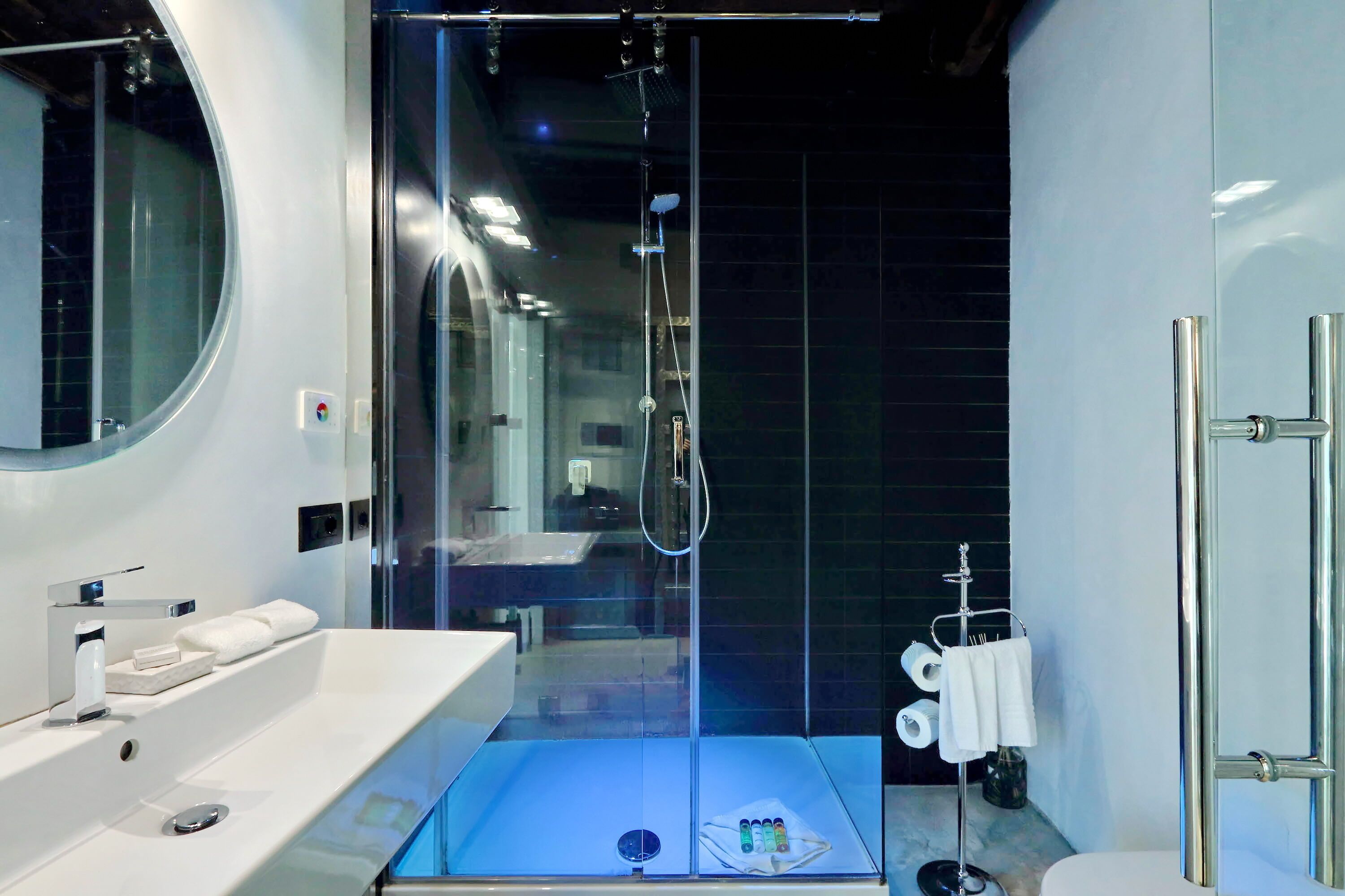 A modern bathroom with a glass-enclosed shower, a white sink, and a toilet.