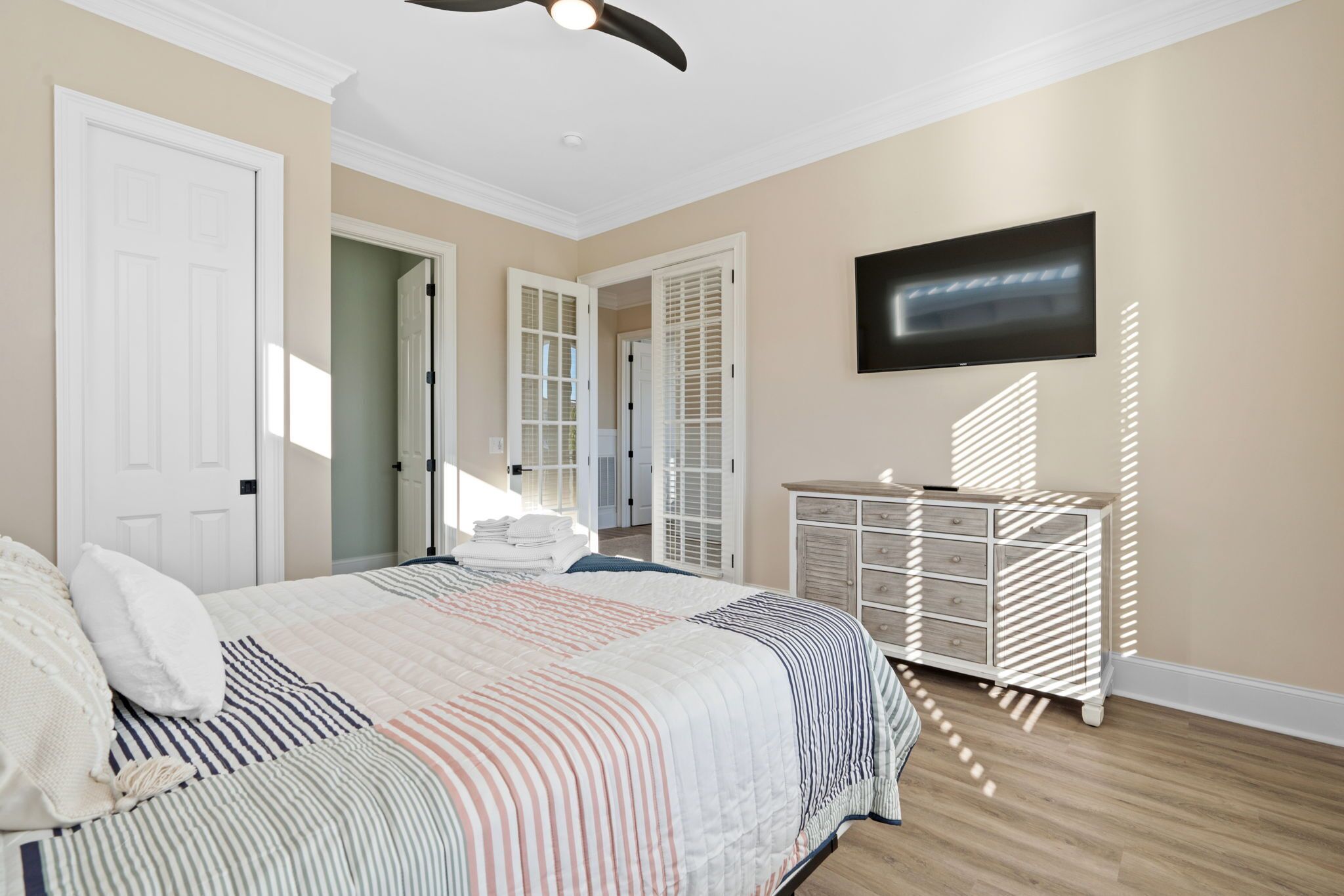 A bedroom with a bed, a dresser, a television, and a closet.