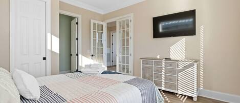 A bedroom with a bed, a dresser, a television, and a closet.
