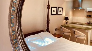 Ein Hotelzimmer mit Bett, Schreibtisch, Stuhl, Spiegel und einer Küchenzeile.