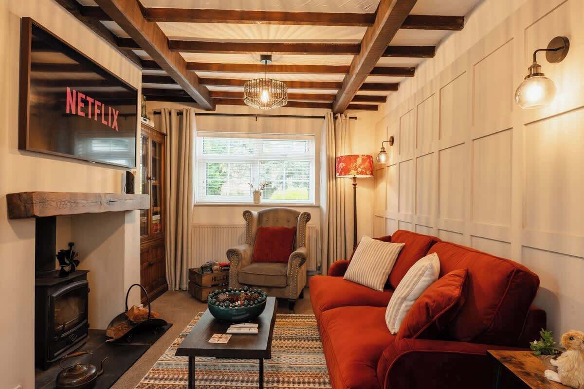Un salón acogedor con chimenea, un sofá rojo, techo de madera y letrero de Netflix.