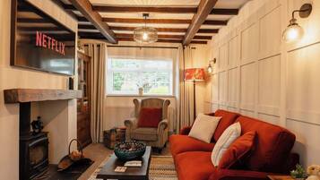 Un salón acogedor con chimenea, un sofá rojo, techo de madera y letrero de Netflix.