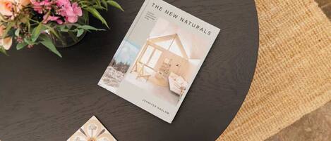 Un libro titulado 'The New Naturals' de Jennifer Kaslam sobre una mesa redonda con una planta en maceta y un adorno.