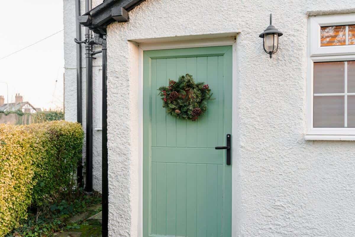 A house with a green door, a wreath, and a window with a white frame.