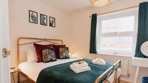 A bedroom with a bed, a bedside table, a window with curtains, and wall art. - Stylish Chester Stay, Free Parking, Private Garden (Cheshire West and Chester)