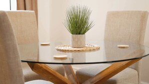 A round glass table with a woven placemat, surrounded by two beige upholstered chairs. - Park and walk to city centre!  Cosy terrace (Handbridge)