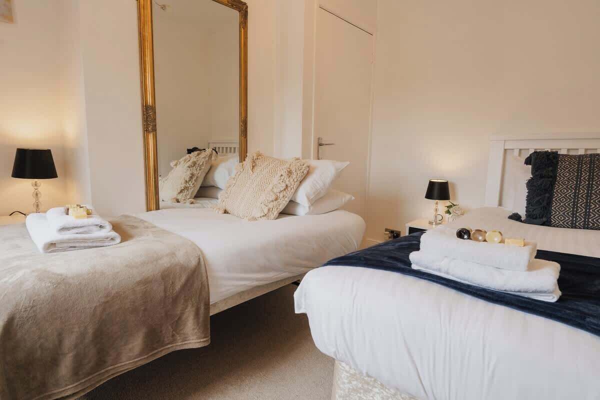 A hotel room with two beds, a large mirror, bedside lamps, and towels.