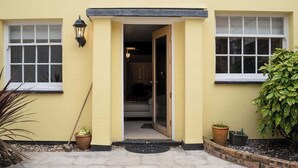 A yellow building with a door leading to an interior, two windows, and potted plants. - 2 Bed - City Centre on your doorstep Parking! (Cheshire West and Chester)