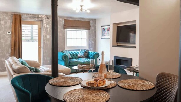 A dining area with a round table, woven placemats, a bottle, and glasses. - 2 Bed - City Centre on your doorstep Parking! (Cheshire West and Chester)