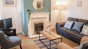 A living room with a fireplace, a sofa, a TV, and a coffee table. - Budget friendly Edwardian home - Sleeps up to 7 (Cheshire West and Chester)