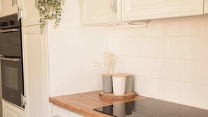 A kitchen with white cabinets, a wooden countertop, and a black induction cooktop. - Budget friendly Edwardian home - Sleeps up to 7 (Cheshire West and Chester)