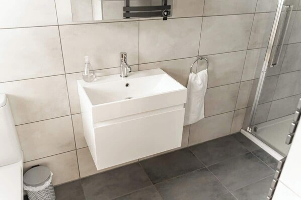 A bathroom with a white sink, a towel rack, and a shower area.