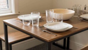 A dining table with clear glassware, plates, and a bowl, set for a meal.