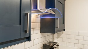 A kitchen with dark cabinets, a visible toaster, and a modern range hood with blue lighting.