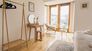 A bedroom with a bed, a desk, a chair, a hanging rack, a window, and a view of the outside. - 5 Bedroom Home, Sleeps 10, Nr Royal Liverpool Golf (Merseyside)