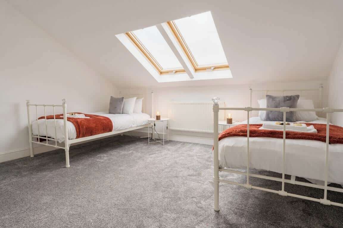 A dormitory room with two beds, a skylight, and a radiator.
