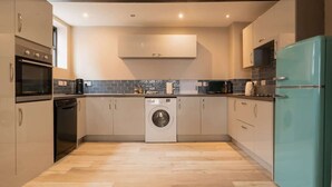Eine moderne Küche mit Waschmaschine, Backofen und einem türkisfarbenen Kühlschrank.