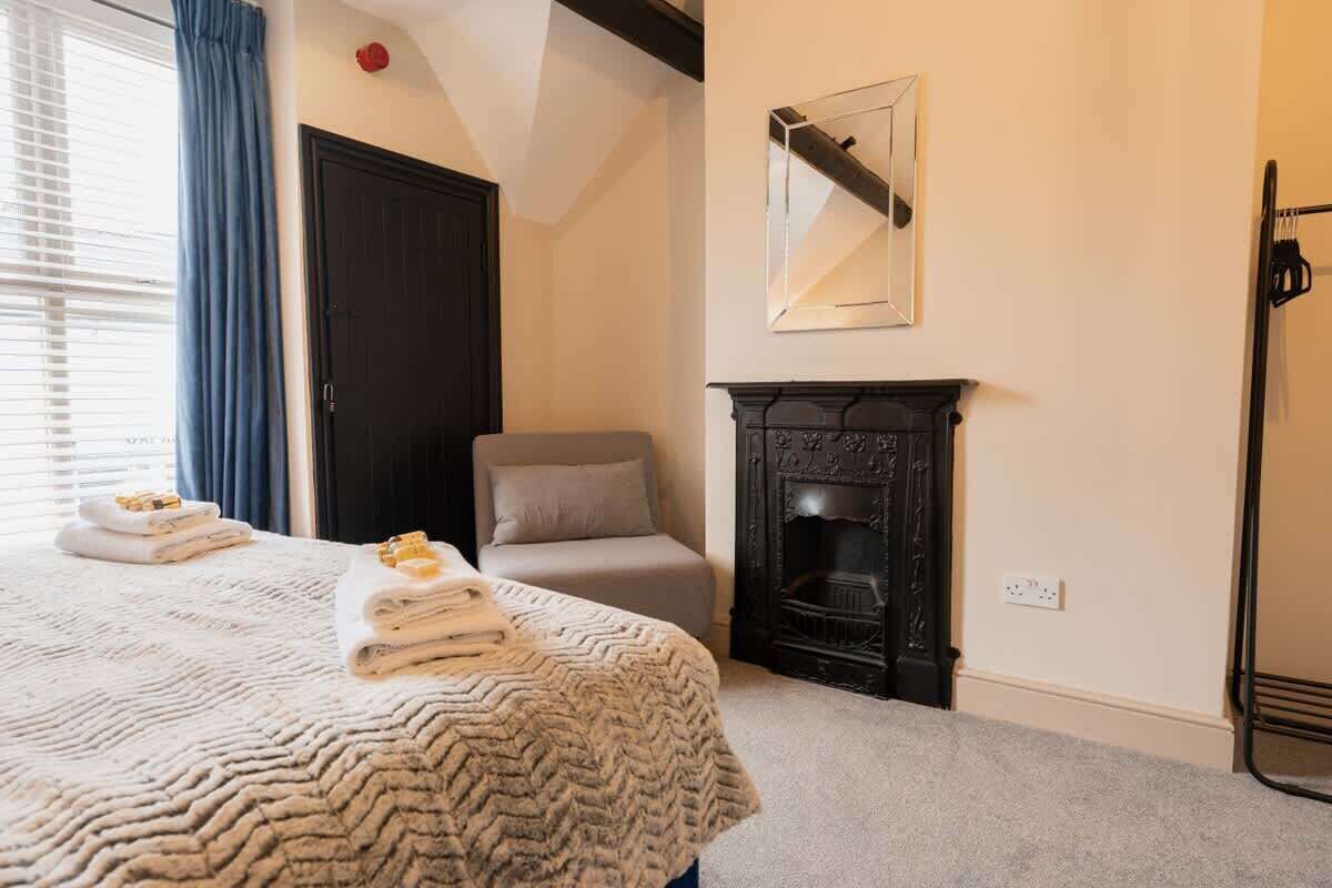 Un dormitorio con cama, chimenea, puerta y ventana con cortinas.