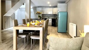 A modern kitchen with a dining area, featuring a table set for breakfast with orange juice and pastries. - Well Decorated Home, Charming Village Location (Tarvin)