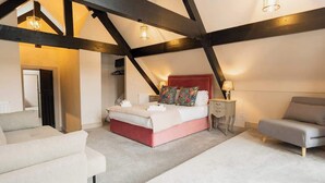 A bedroom with a bed, bedside tables, a sofa, and exposed wooden beams. - Well Decorated Home, Charming Village Location (Tarvin)