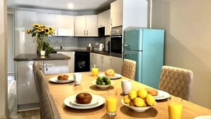 A modern kitchen with a dining table set for breakfast, including plates of food and drinks. - Well Decorated Home, Charming Village Location (Tarvin)