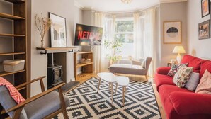 A living room with a fireplace, a red sofa, a TV, and a patterned rug. - Sleeps 6, off street parking, close to city (Cheshire West and Chester)