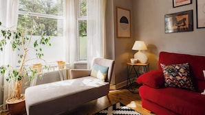 A living room with a sofa, a red couch, a lamp, and a potted plant. - Sleeps 6, off street parking, close to city (Cheshire West and Chester)