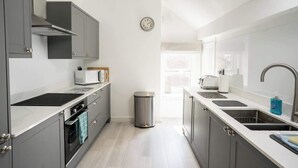 Une cuisine moderne avec des meubles gris, un évier en acier inoxydable et un four à micro-ondes.