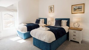 Une chambre avec deux lits, une table de chevet et une fenêtre.