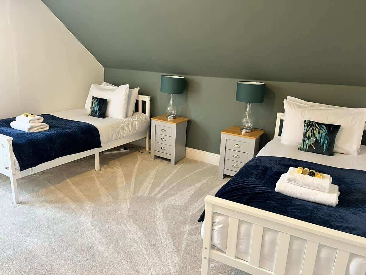 A bedroom with two beds, nightstands, and lamps.