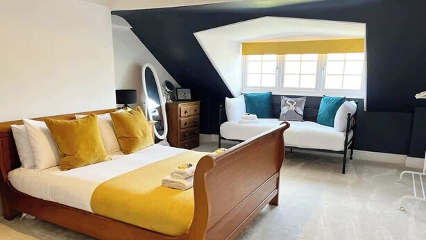 Een slaapkamer met een bed, een kaptafel, een dressoir en een raam met uitzicht.