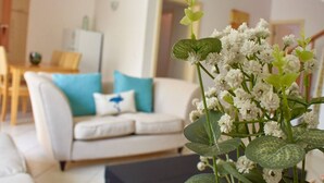 A living room with a white sofa, a coffee table, and a vase of white flowers.