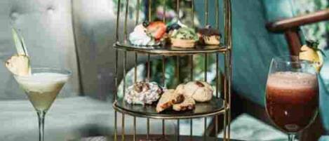 A tiered dessert stand with pastries and a martini glass on the left, and a wine glass on the right.