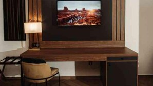 A modern room with a wooden desk, a chair, a television mounted on the wall, and a lamp. - City Hotel by Waves (Kenitra)